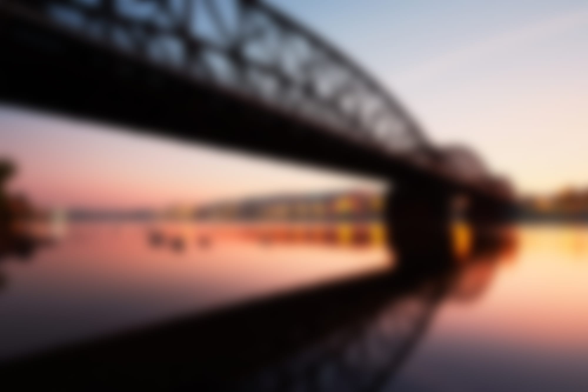 blurry image of sunrise behind a bridge